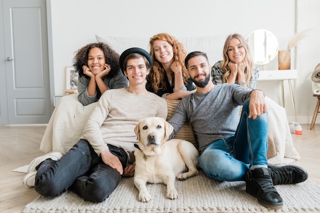 Two smiling guys and white labrador relaxing on the floor