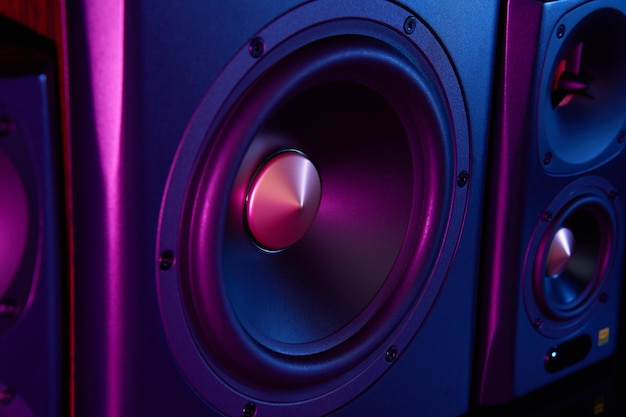 Two sound speakers and subwoofer on dark background with neon lights