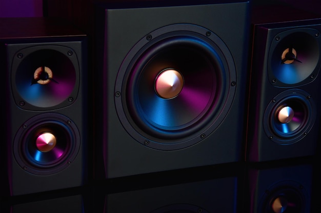 Two sound speakers and subwoofer on dark background with neon lights