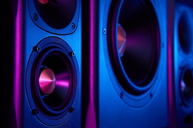 Two sound speakers and subwoofer on dark background with neon lights