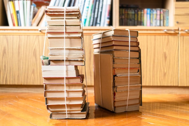 Two stacks of books tied with rope near bookcase