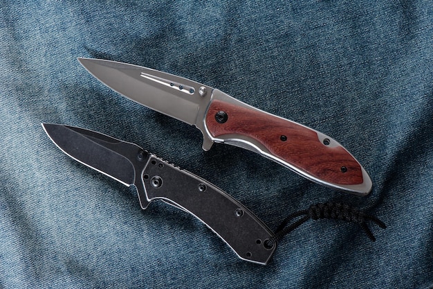 Two stainless steel folding knifes over denim jacket