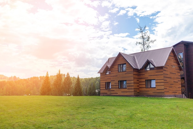 Two storey wooden cottage with windows nature with a green lawn. Sale or purchase of new houses.