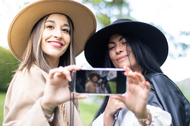 Two stylish friends both grabbing a cell phones to take a selfie