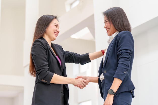 Two Successful businesswoman shake hand with partner to celebration partnership and teamwork business deal