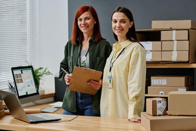 Two successful female volunteers standing by workplace in storage room