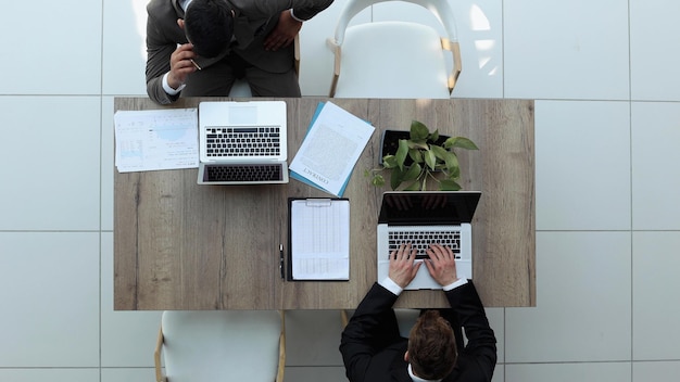 Two successful smiling businessmen are working on a laptop view from above