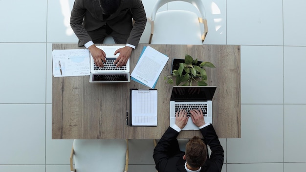 Two successful smiling businessmen are working on a laptop view from above