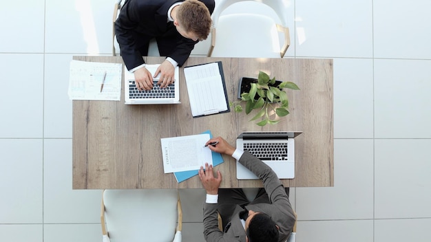 Two successful smiling businessmen are working on a laptop view from above