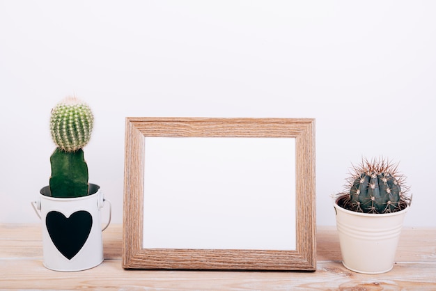 Two succulent plants on sides of empty photo frame on wooden desk