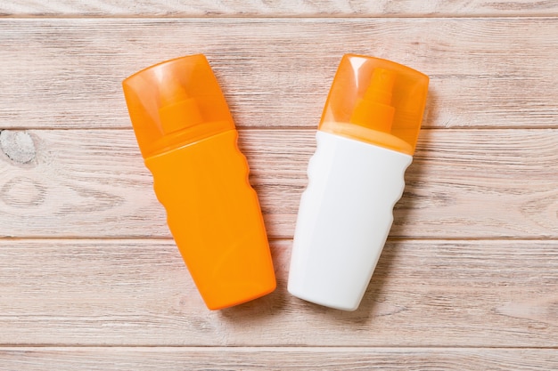 Two Sunscreen bottles on a bright wooden background, top view.