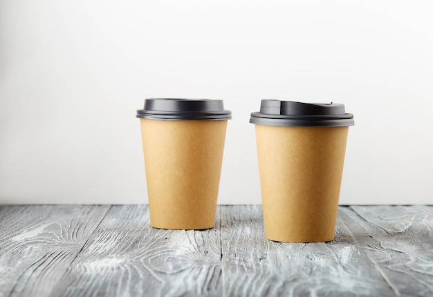 Two take away paper coffee cups on grey wooden background