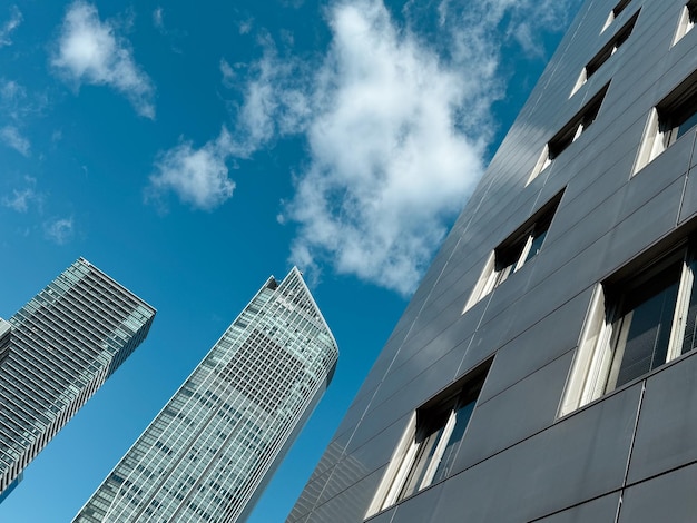 two tall buildings with a blue sky and one with a few clouds in the background