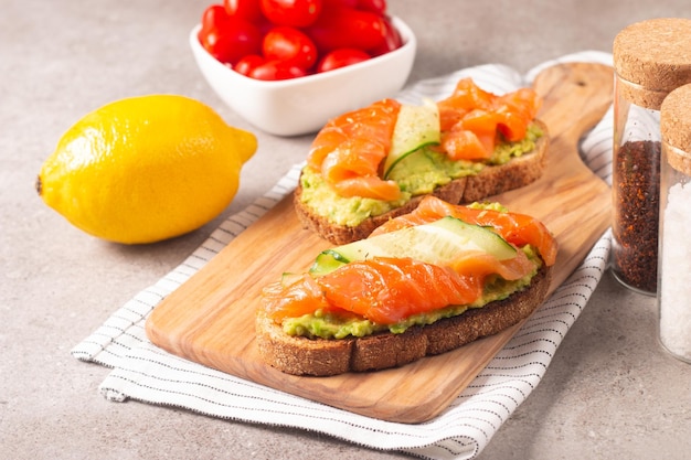 Two tasty open salmon sandwiches with avocado and cucumber. Morning healthy breakfast. Top view.