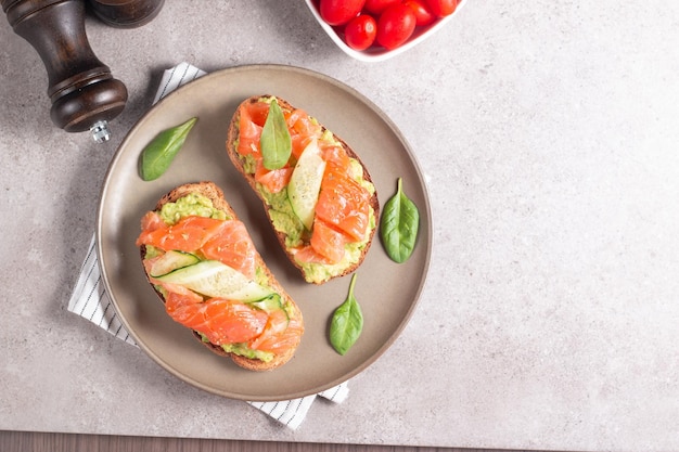 Two tasty open salmon sandwiches with avocado and cucumber. Morning healthy breakfast. Top view.