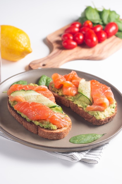 Two tasty open salmon sandwiches with avocado and cucumber. Morning healthy breakfast. Top view.