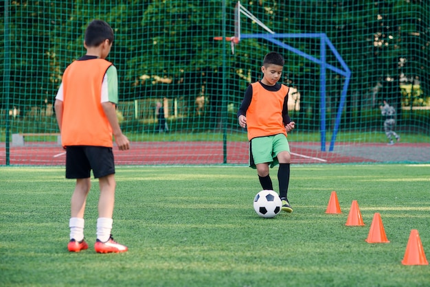 Two teen players passes soccer ball each other on football stadium.