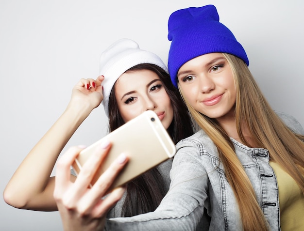 Two teenage girls friends in hipster outfit make selfie on a phone