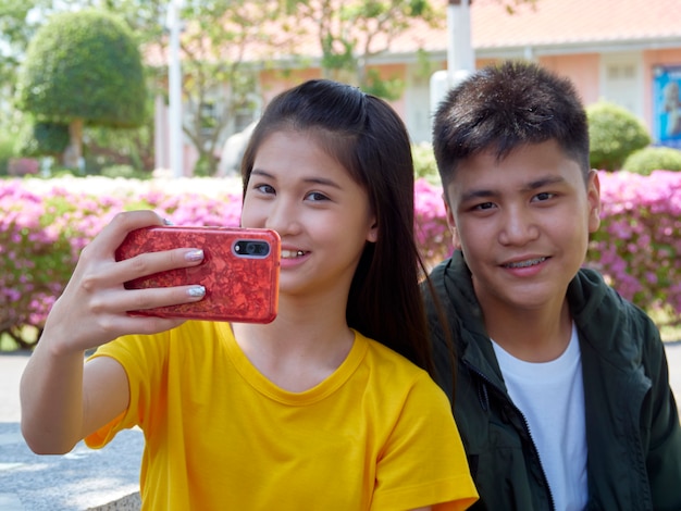 Two teenage use their smartphones outdoors