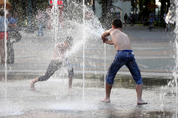 Two teenagers playing with water in fountain