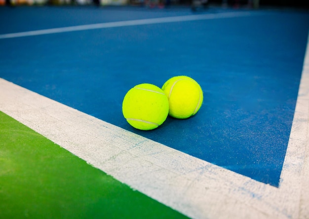 Two tennis balls on blue and green court