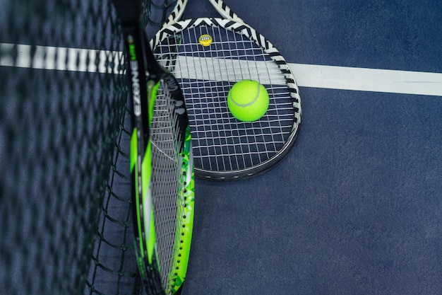 Two tennis rackets and balls leaned against the net Horizontal photo