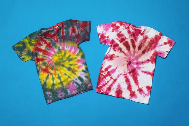 Two tie dye T-shirts on a blue background. Flat lay.