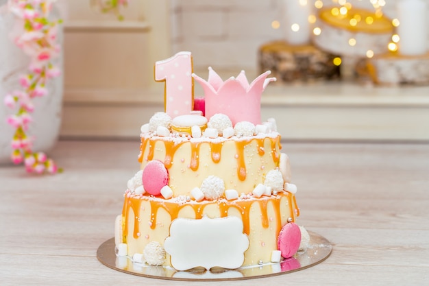 Two-tier cake for the first birthday. on top of the cake the number 1 and cardboard.