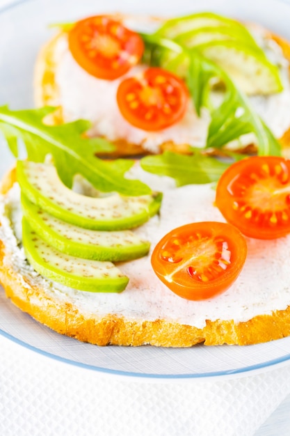 Two toasts with avocado and arugula on a plate