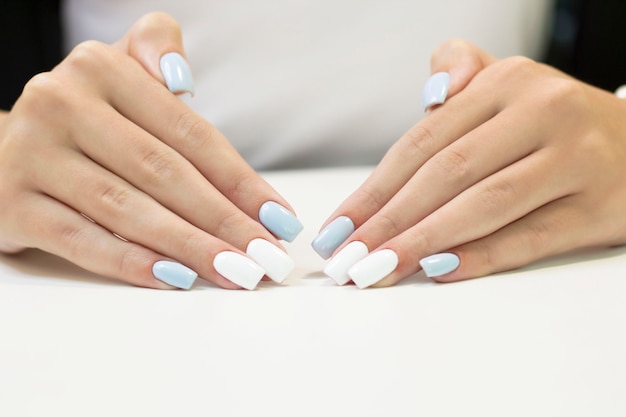 Two-tone manicure with blue and white nail Polish on a white