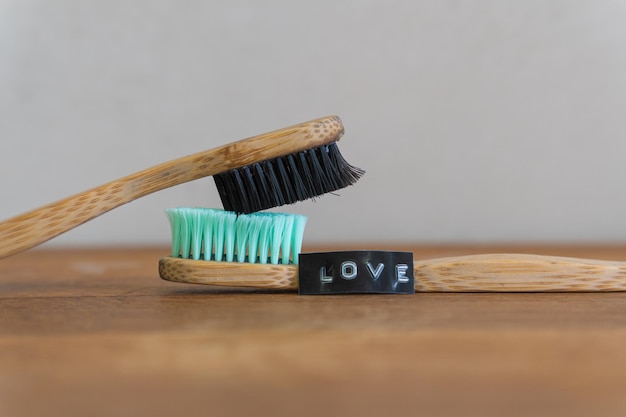 Two toothbrushes on top of each other next to word love on top of each other next to word love