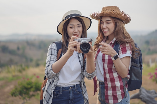 Two tourist woman taking a photo with camera in nature