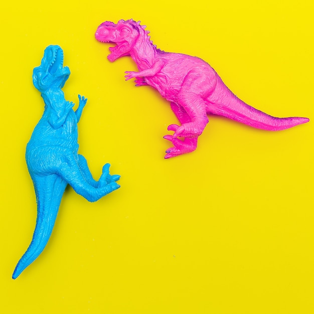 Two Toys dinosaurs on a colored background. Flat lay minimal art