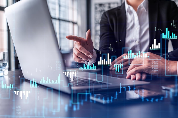 Two traders researching historic data to predict stock market behavior using laptop Internet trading concept Forex and financial hologram chart Forecasting and planning