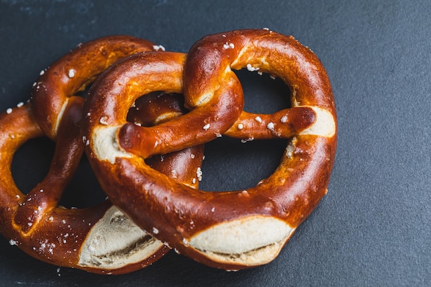 Two traditional soft Octoberfest pretzels on black background