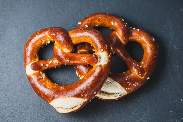 Two traditional soft Octoberfest pretzels on black background