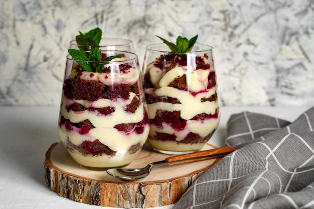 Two transparent glass with layered dessert chocolate cake and whipped cream berries