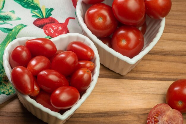 Two types of tomato inside a white bowl on a wooden table