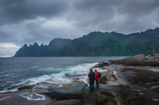 Two unrecognizable people stand on tungeneset beach on senja island in norway