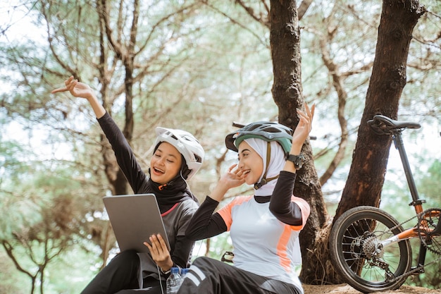 Two veiled girls use earphones to hear songs while cycling