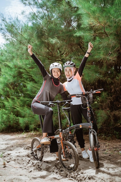 Two veiled girls with fists clenched while cycling together