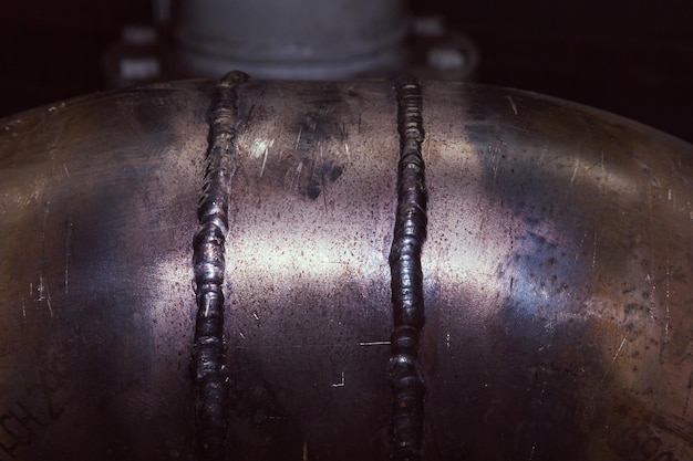 Two vertical welds on a stainless steel pipe closeup