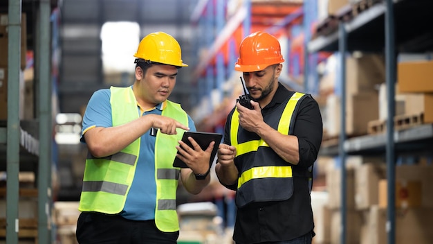 Two Warehouse workers talking about logistics and distribution in warehouse stock checking