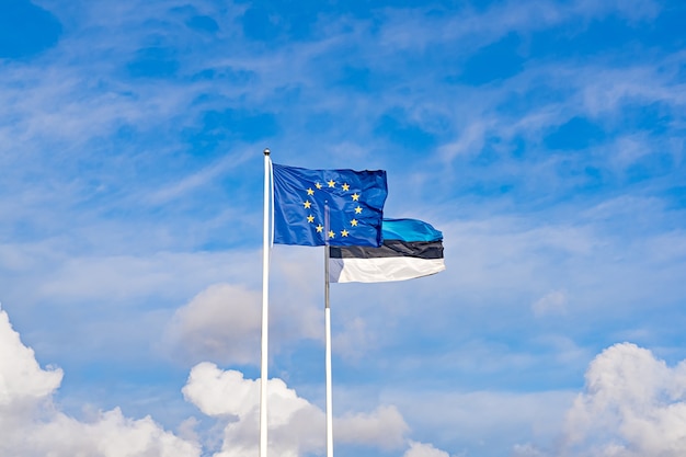 Two waving flags of European Union and Estonia against blue sky. Estonian independence day is celebrated on February 24