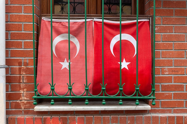 Two waving turkish flag in window with grate brick wall