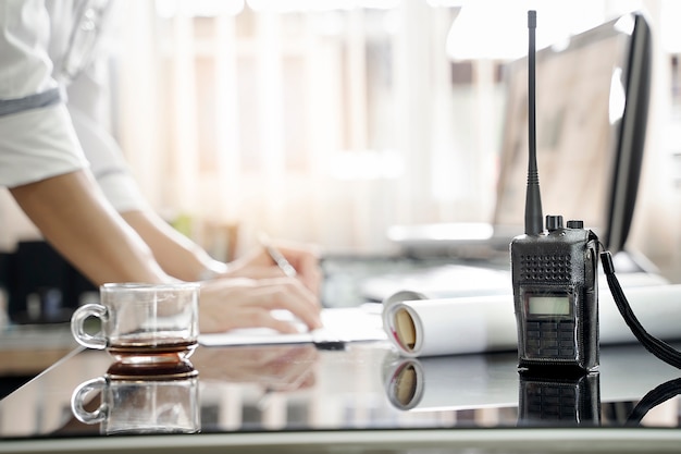 Two way radios on table with blur background of men working