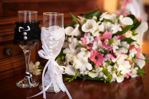 Two wedding glasses and bridal bouquet on stone in summer garden