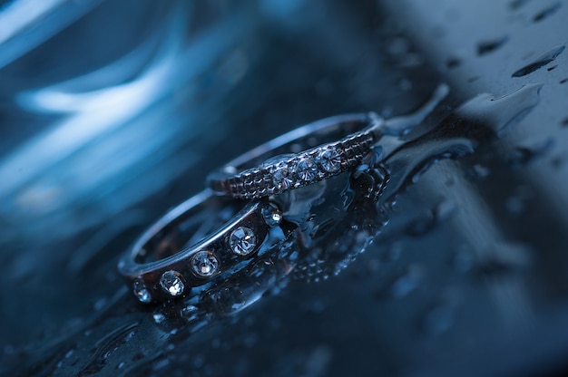 Two wedding rings on a blue background with drops