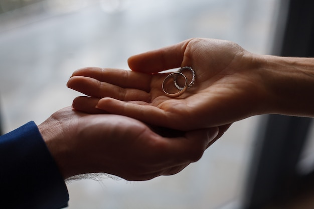 two wedding rings in the hands of the newlyweds close up.  wedding ceremony. wedding day. romantic moment.   the couple exchanges the wedding rings. just married couple.