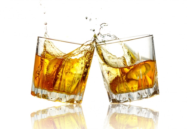 Two whiskey glasses clinking together, isolated